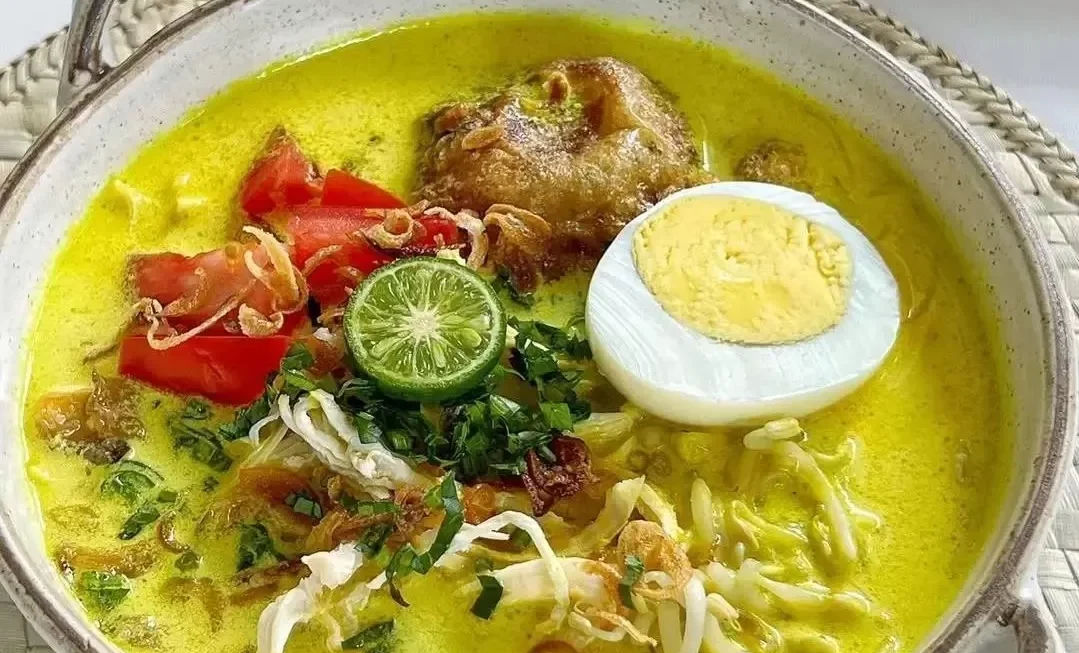 Semangkuk Soto Medan kuah santan kuning dengan ayam, telur rebus, dan jeruk nipis